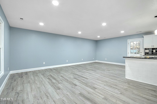 unfurnished living room with recessed lighting, baseboards, and light wood finished floors