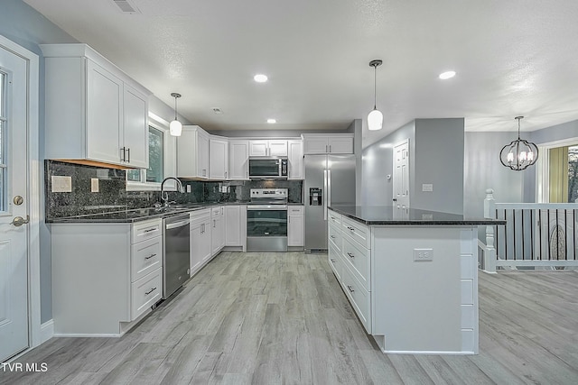 kitchen featuring dark countertops, appliances with stainless steel finishes, light wood-style flooring, and a center island