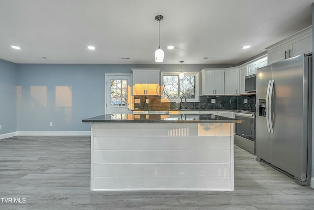 kitchen with stove, light wood-style floors, stainless steel refrigerator with ice dispenser, tasteful backsplash, and a center island