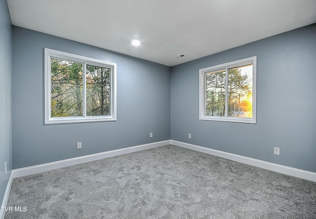 carpeted empty room featuring visible vents and baseboards