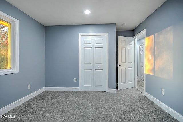 unfurnished bedroom with carpet, baseboards, and a closet