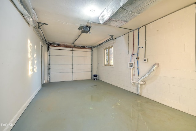 garage with concrete block wall, a garage door opener, and baseboards