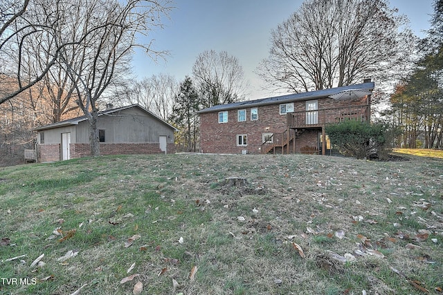 back of house with stairs, a deck, a yard, and brick siding