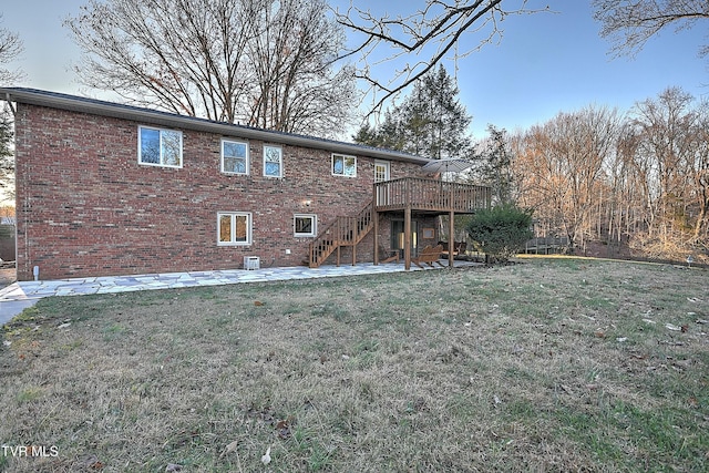 back of property featuring brick siding, stairway, a wooden deck, a lawn, and a patio area