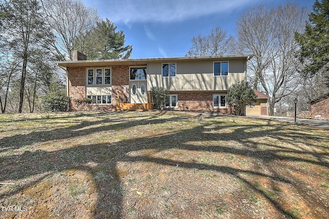 rear view of house with a yard, brick siding, and a chimney