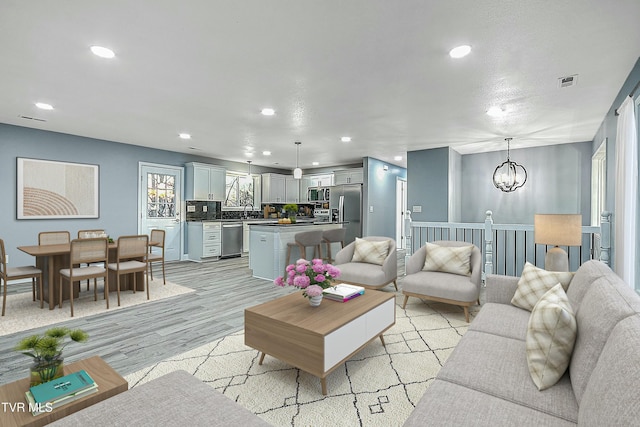 living area with a notable chandelier, recessed lighting, visible vents, and light wood finished floors