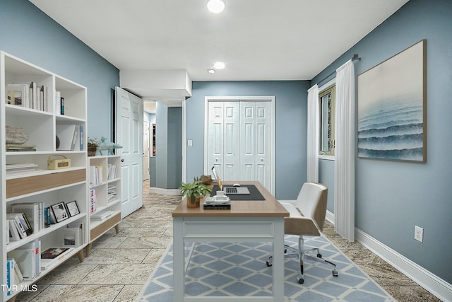 office area featuring baseboards and stone tile flooring