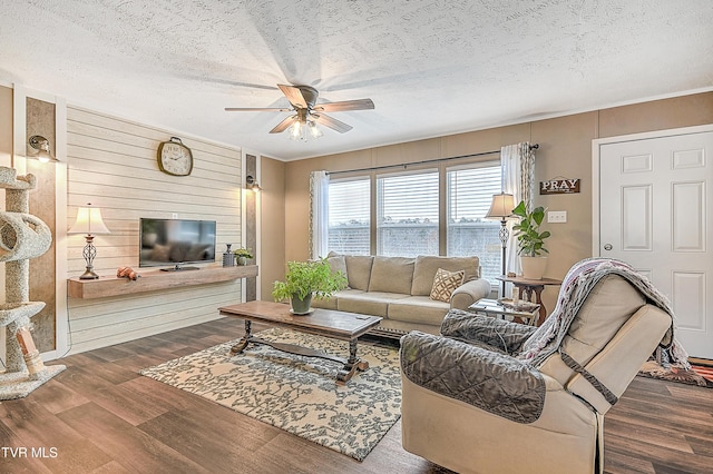 living room with hardwood / wood-style flooring, ceiling fan, and a textured ceiling