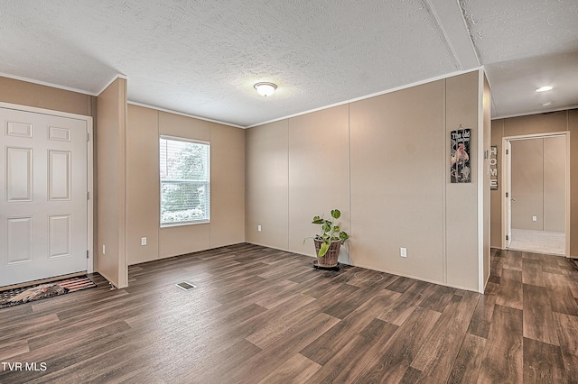 spare room featuring ornamental molding, dark wood-type flooring, and a textured ceiling