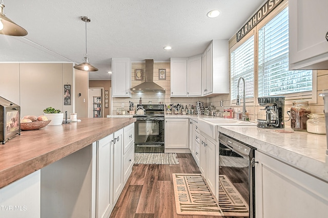 kitchen with decorative light fixtures, dishwasher, white cabinetry, black electric range oven, and wall chimney range hood