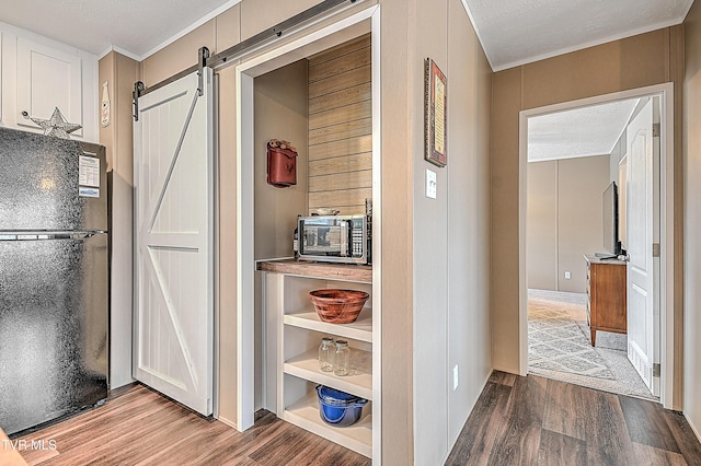 interior space with a barn door, black fridge, hardwood / wood-style floors, and a textured ceiling