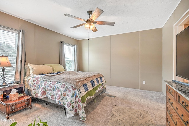 bedroom featuring ceiling fan, light colored carpet, and a textured ceiling