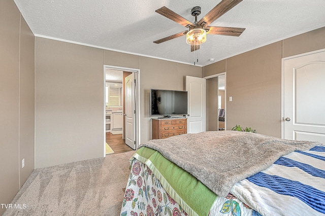 bedroom featuring ceiling fan, light colored carpet, ensuite bath, and a textured ceiling