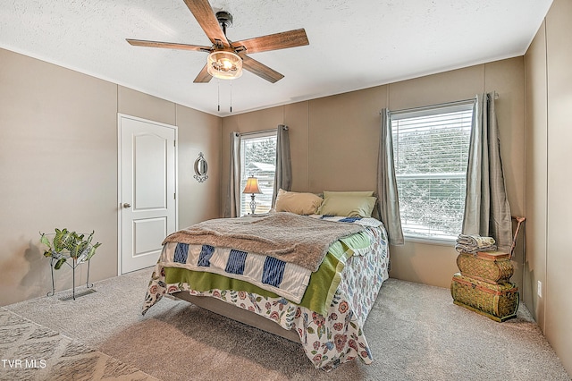 bedroom with ceiling fan, carpet flooring, and a textured ceiling