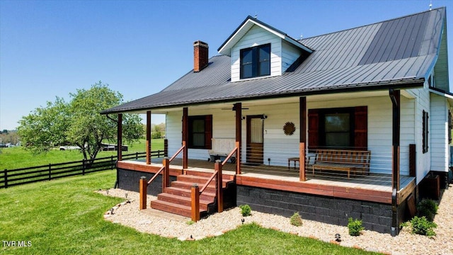 rear view of house with covered porch and a yard