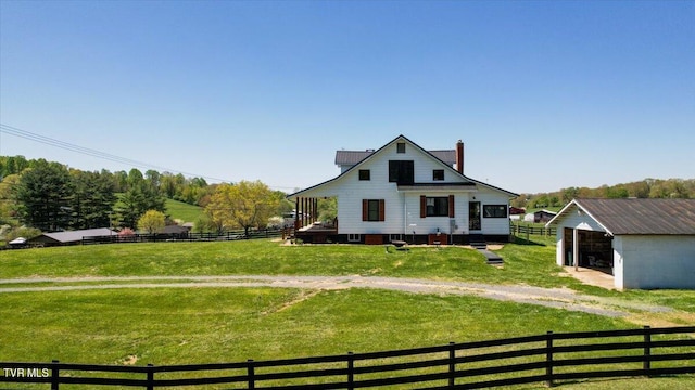 rear view of property featuring an outbuilding, a yard, and a rural view