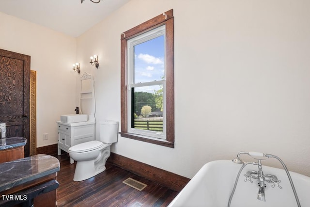 bathroom with hardwood / wood-style floors, vanity, toilet, and a bathing tub