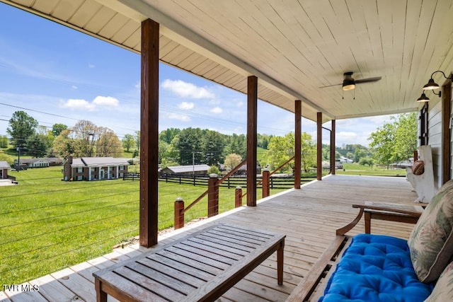 wooden terrace featuring a lawn, ceiling fan, and a porch