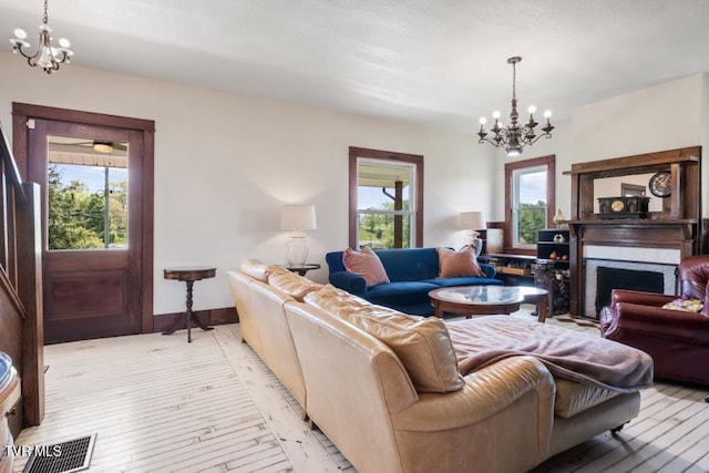 living room featuring a chandelier, light wood-type flooring, and a healthy amount of sunlight