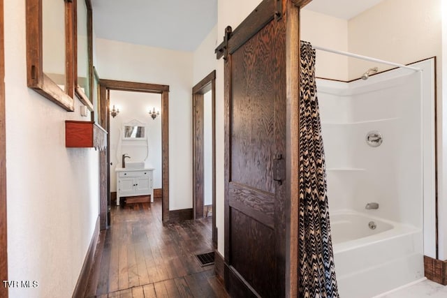 bathroom with hardwood / wood-style floors, shower / bath combo, and sink