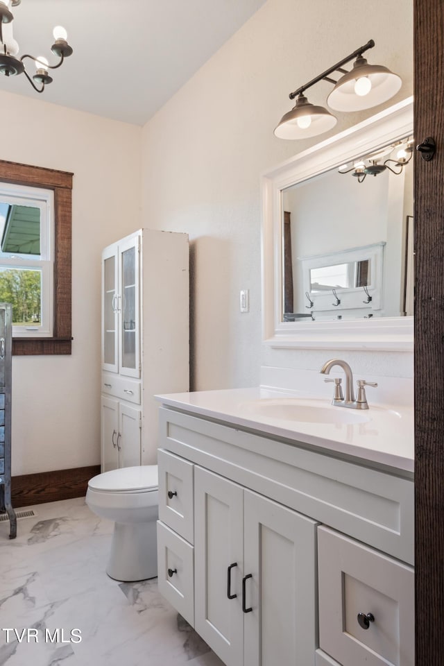 bathroom featuring an inviting chandelier, vanity, and toilet