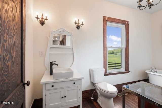 bathroom with vanity, hardwood / wood-style flooring, toilet, and a notable chandelier