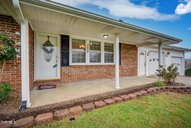 view of exterior entry with a garage and brick siding