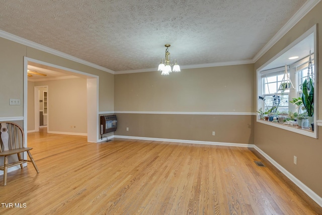 unfurnished room featuring a notable chandelier, ornamental molding, a textured ceiling, light wood-type flooring, and baseboards