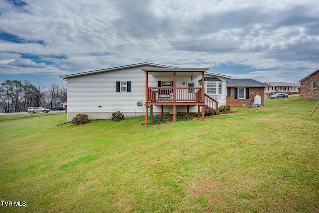 back of property featuring a deck, a lawn, and brick siding