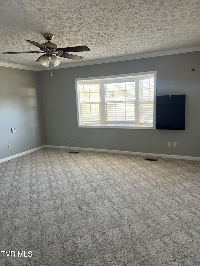 carpeted empty room featuring a textured ceiling, baseboards, visible vents, and crown molding