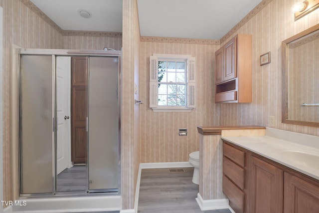 bathroom with hardwood / wood-style flooring, vanity, toilet, and an enclosed shower