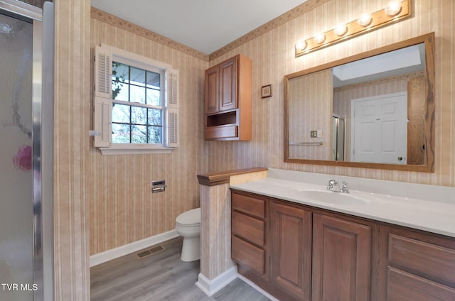 bathroom featuring hardwood / wood-style flooring, vanity, toilet, and a shower with door