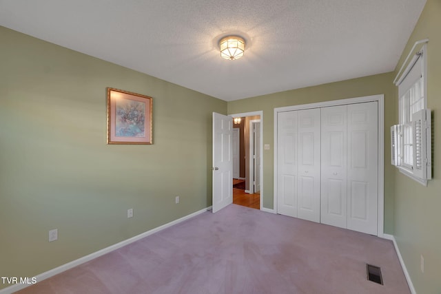 unfurnished bedroom with a closet, light colored carpet, and a textured ceiling