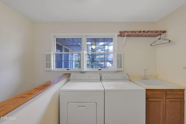 clothes washing area featuring sink, cabinets, and independent washer and dryer