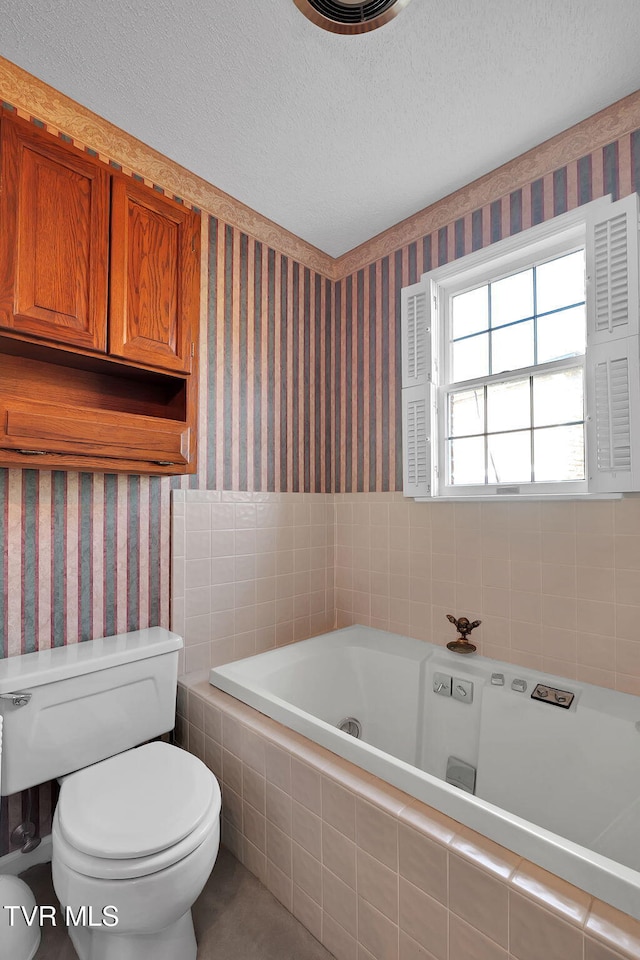 bathroom featuring a textured ceiling, tiled bath, and toilet