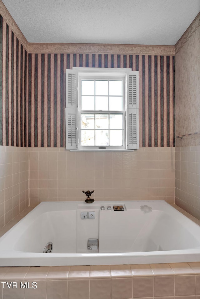 bathroom featuring a textured ceiling and a relaxing tiled tub