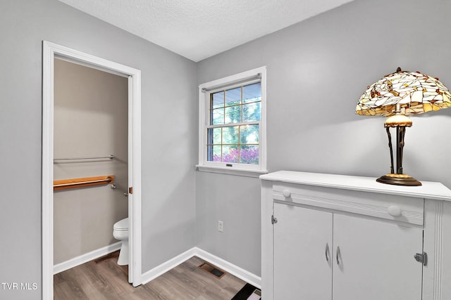 bathroom featuring hardwood / wood-style floors, toilet, and a textured ceiling