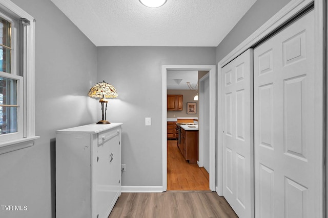 hallway with a textured ceiling and light hardwood / wood-style flooring