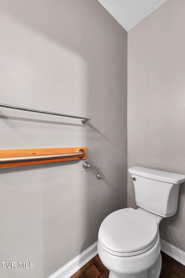 bathroom with hardwood / wood-style floors, a textured ceiling, and toilet