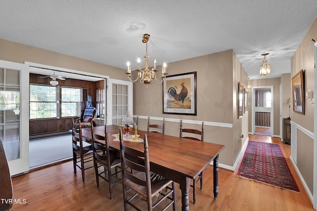 dining room featuring baseboard heating, ceiling fan with notable chandelier, a textured ceiling, and hardwood / wood-style flooring