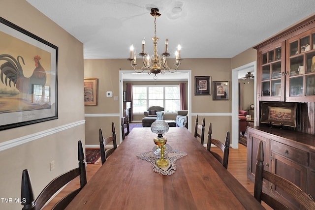 dining space with a notable chandelier, a textured ceiling, and light hardwood / wood-style flooring