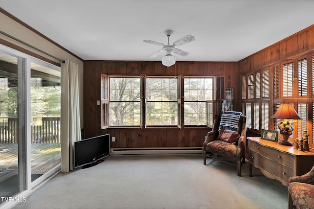 sitting room with light carpet, ceiling fan, wood walls, and a baseboard heating unit