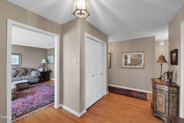 hall featuring wood-type flooring, a textured ceiling, and an inviting chandelier