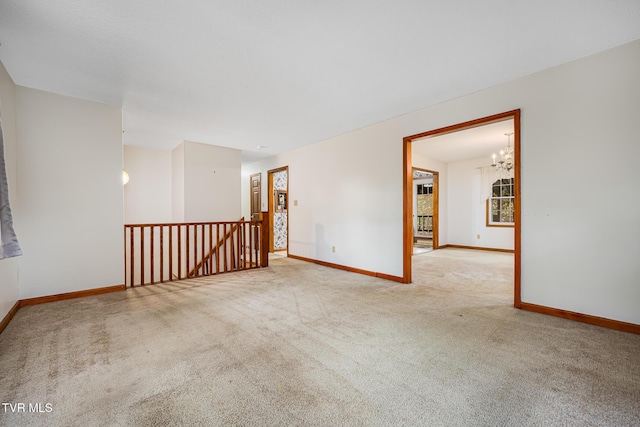 empty room with light colored carpet and an inviting chandelier