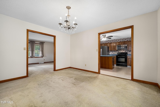 empty room featuring ceiling fan with notable chandelier, light colored carpet, and a textured ceiling