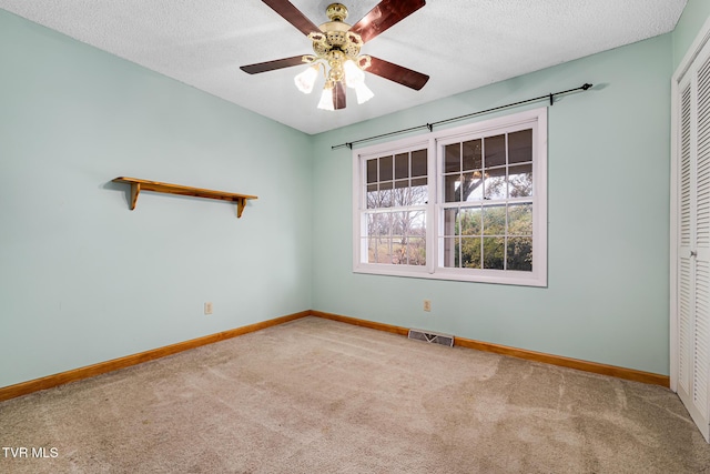 empty room with a textured ceiling, carpet floors, and ceiling fan