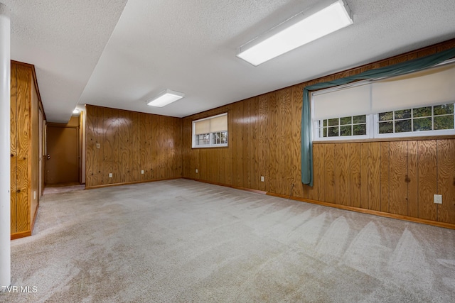 unfurnished room with light carpet, a textured ceiling, and wooden walls