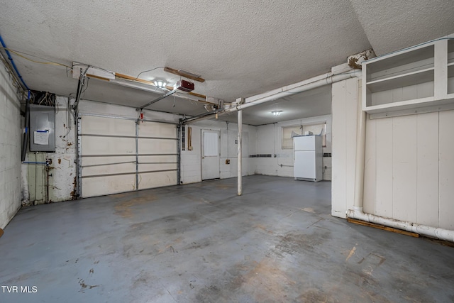 garage with white refrigerator, electric panel, and a garage door opener