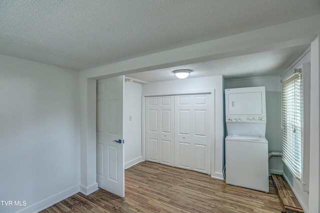 interior space featuring a textured ceiling, light wood-type flooring, and stacked washing maching and dryer