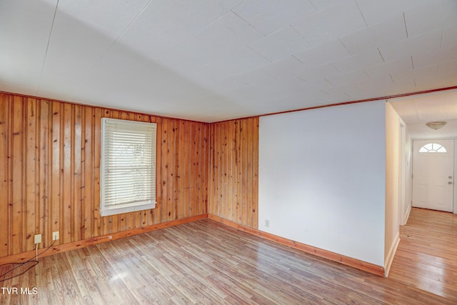 unfurnished room with wood walls and light hardwood / wood-style flooring